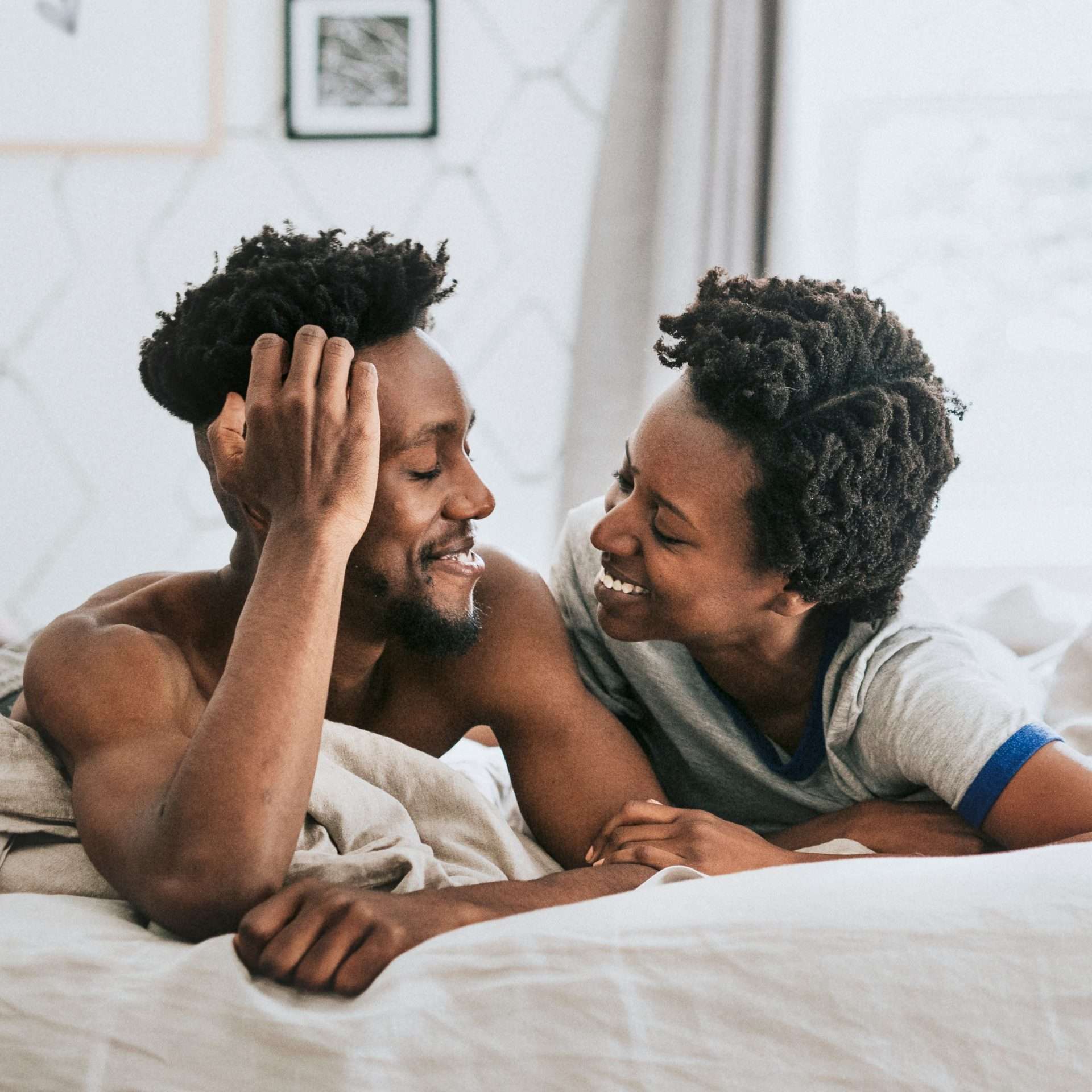 A black couple in bed together, smiling